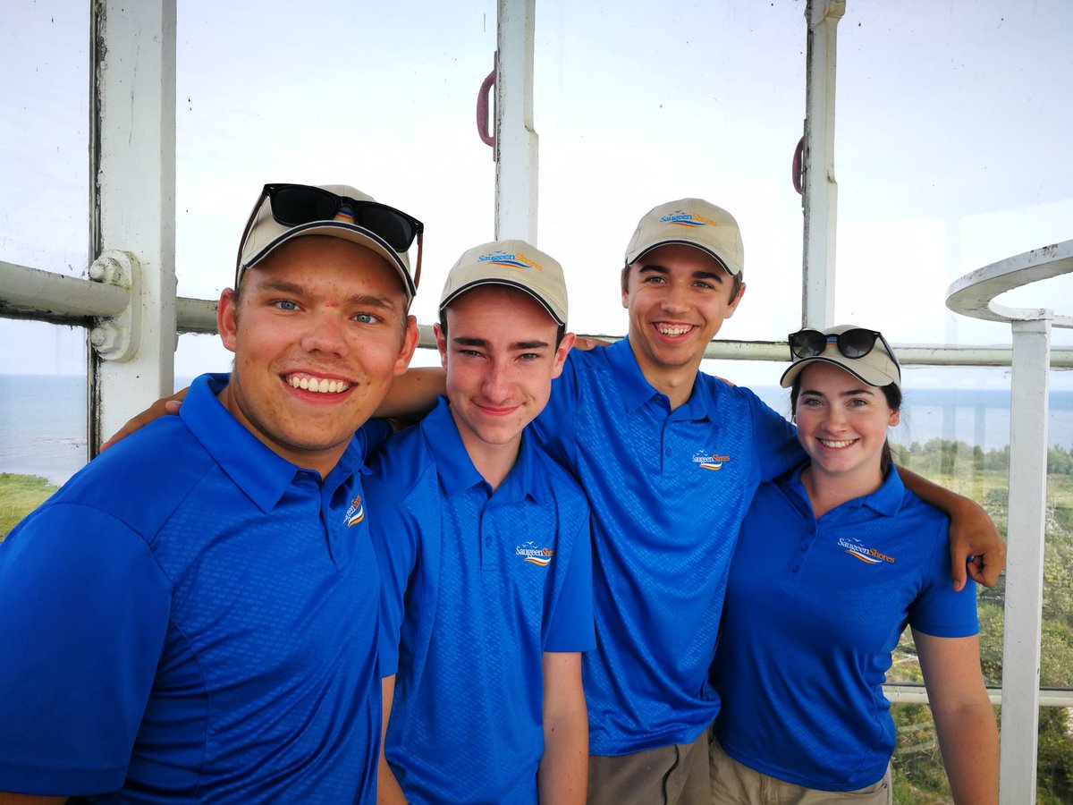 Four teens in blue shirts at the top of lighthouse